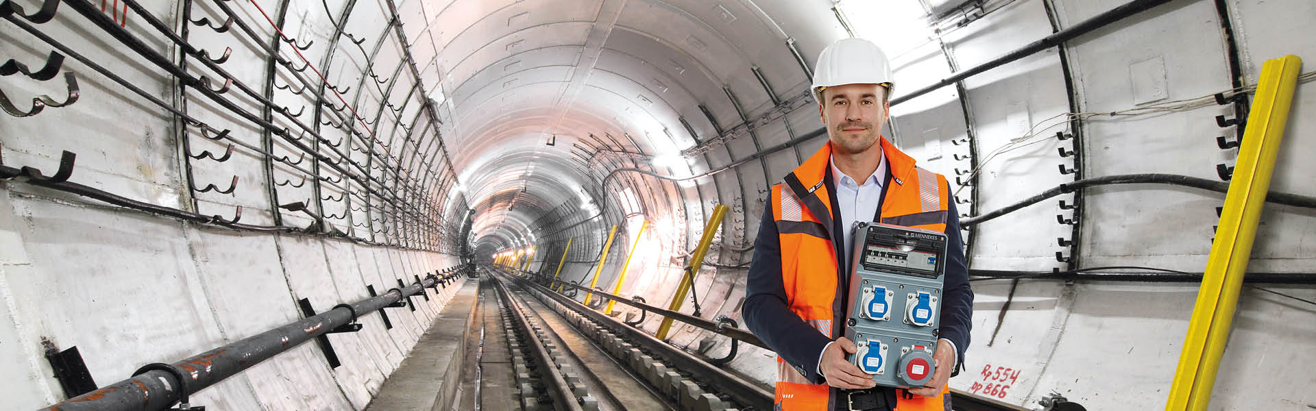 Ein Mann steht in einem Tunnel und hält eine AMAXX Kombination in den Händen