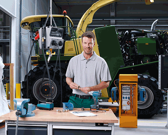 ein Mann steht an einer Werkbank vor einem gelben MENNEKES Stromverteiler und einem Trecker