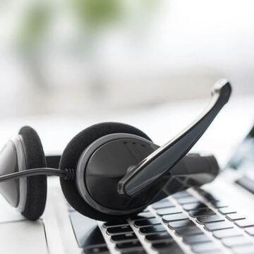 Ein Headset liegt auf der Tastatur eines Laptops